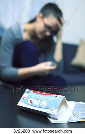 Stock Image - France, young woman at home using Hiv test.. Fotosearch