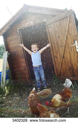 Little boy happily throwing seeds to the chickens in front of a henhouse View Large Photo Image Stock Photo - Little boy happily throwing seeds to the chickens in front of a henhouse. Fotosearch