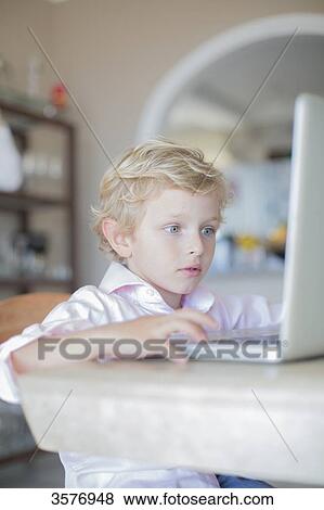 Stock Photo - Little boy with laptop at home. Fotosearch