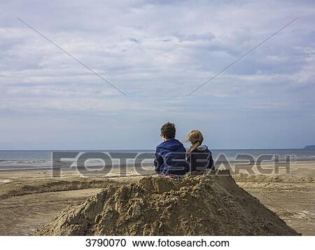 Stock Image - Normandy, Two kids on the beach seen from behind on a pile of sand. Fotosearch