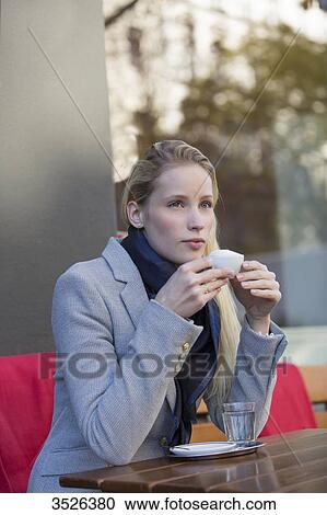 Pensive pretty woman enjoying a cup of coffee in city center View Large Photo Image Stock Image - Pensive pretty woman enjoying a cup of coffee in city center. Fotosearch