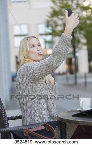 Playful pretty young woman doing a selfie in a Cafe in city center View Large Photo Image Stock Photo - Playful pretty young woman doing a selfie in a Cafe in city center. Fotosearch