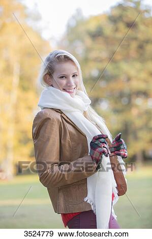 Stock Photo - Portrait of a content pretty blonde woman with gloves and scarf in Autumn smiling at camera. Fotosearch