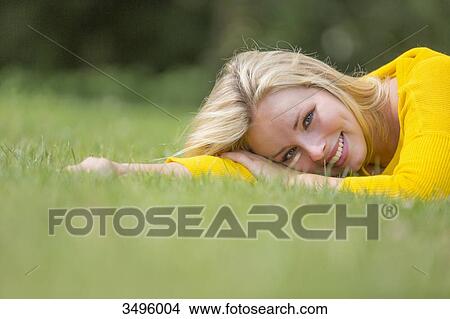 Portrait of a pretty blond woman lying down in the park smiling at camera View Large Photo Image Picture - Portrait of a pretty blond woman lying down in the park smiling at camera. Fotosearch