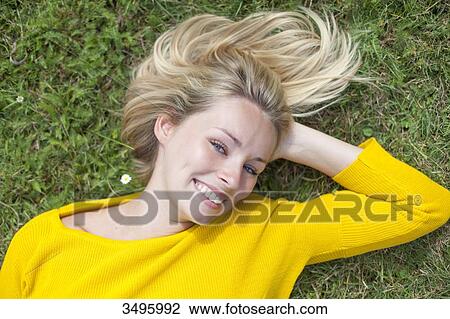 Portrait of a pretty blond woman lying down in the park smiling at camera View Large Photo Image Stock Image - Portrait of a pretty blond woman lying down in the park smiling at camera. Fotosearch