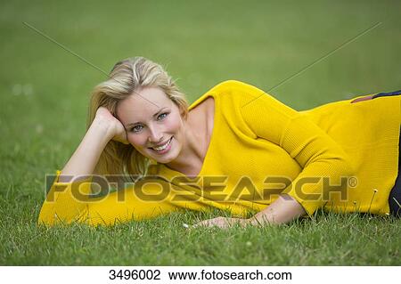 Portrait of a pretty blond woman lying down in the park smiling at camera View Large Photo Image Stock Image - Portrait of a pretty blond woman lying down in the park smiling at camera. Fotosearch