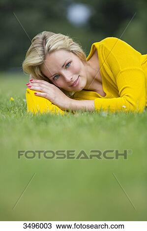 Portrait of a pretty blond woman lying down in the park smiling at camera View Large Photo Image Stock Image - Portrait of a pretty blond woman lying down in the park smiling at camera. Fotosearch