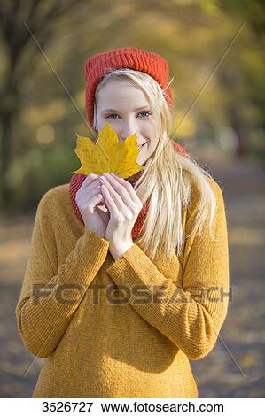 Portrait of a pretty blonde woman in park in autumn with leaf covering partially her face View Large Photo Image Stock Photo - Portrait of a pretty blonde woman in park in autumn with leaf covering partially her face. Fotosearch