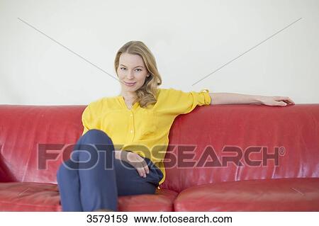 Stock Photo - Portrait of a pretty blonde woman on the couch looking at camera. Fotosearch
