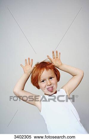 Portrait of a red-haired little girl indoors sticking her tongue out and putting her hands in the air View Large Photo Image Stock Photography - Portrait of a red-haired little girl indoors sticking her tongue out and putting her hands in the air. Fotosearch