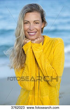 Stock Image - Portrait of a smiling young blonde woman in yellow sweet in the sea.. Fotosearch