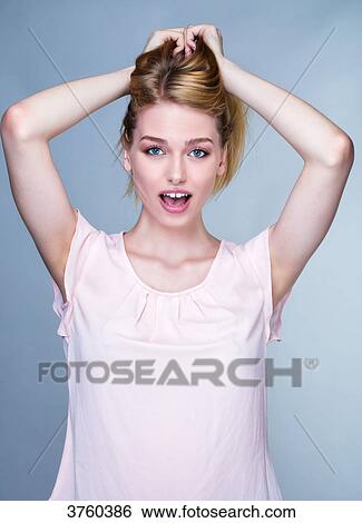 Stock Photograph - Portrait of a smiling young woman, arms over head. Fotosearch