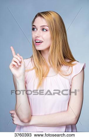 Portrait of a smiling young woman raised finger on the side View Large Photo Image Stock Image - Portrait of a smiling young woman raised finger on the side. Fotosearch