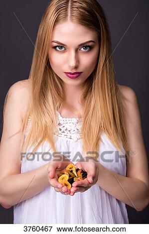 Stock Photo - Portrait of a smiling young woman holding her hands dried fruit. Fotosearch