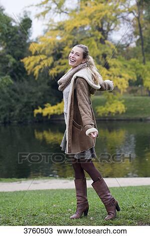 Stock Image - Portrait of a young blonde woman smilling and dynamic at a lke in autumn.. Fotosearch