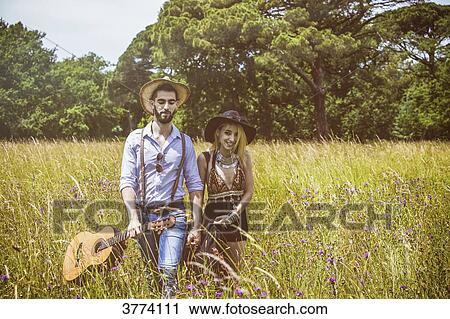 Portrait of a young couple Hipster ride in the country, holding in one hand a guitar the other View Large Photo Image Stock Image - Portrait of a young couple Hipster ride in the country, holding in one hand a guitar the other. Fotosearch