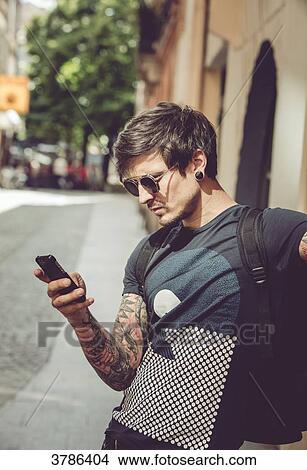 Picture - Portrait of a young man reading an SMS in an urban environment. Fotosearch