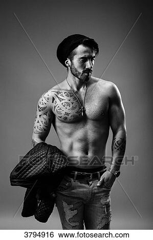 Portrait of a young tattooed man, face, face to the side, hands in pockets, in gray background View Large Photo Image Stock Photograph - Portrait of a young tattooed man, face, face to the side, hands in pockets, in gray background. Fotosearch