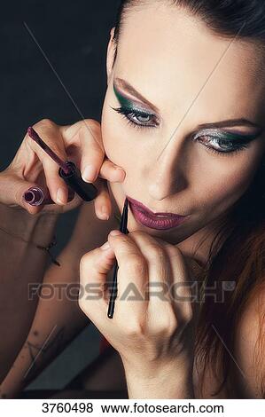 Portrait of a young woman doing makeup lips View Large Photo Image Stock Photo - Portrait of a young woman doing makeup lips. Fotosearch