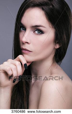 Stock Photograph - Portrait of a young woman, hand under chin, looking toward the lens. Fotosearch