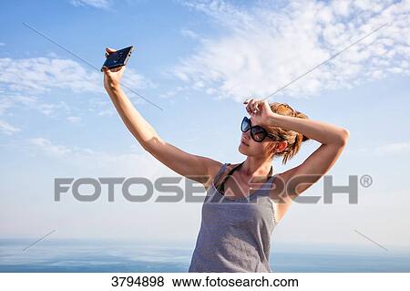 Portrait of a young woman in profile, taking a selfie with smartphone on the heights of Setubal, Lisbon area, Portugal View Large Photo Image Stock Photo - Portrait of a young woman in profile, taking a selfie with smartphone on the heights of Setubal, Lisbon area, Portugal. Fotosearch