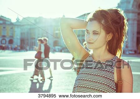 Stock Photography - Portrait of a young woman in profile, one hand behind his head, against the light, on the Place du Commerce, Lisbon, Portugal. Fotosearch