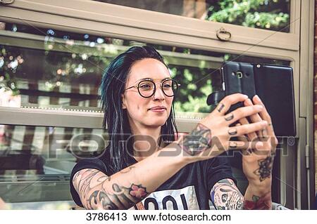 Portrait of a young woman sitting in a restaurant terrace, taking a selfie View Large Photo Image Stock Image - Portrait of a young woman sitting in a restaurant terrace, taking a selfie. Fotosearch