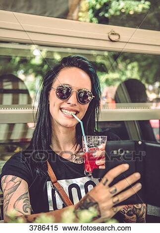 Portrait of a young woman sitting in a restaurant terrace, taking a selfie View Large Photo Image Stock Photography - Portrait of a young woman sitting in a restaurant terrace, taking a selfie. Fotosearch
