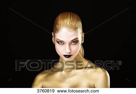 Stock Photo - Portrait of a young woman, the body painted in gold, head down, eyes open. Fotosearch