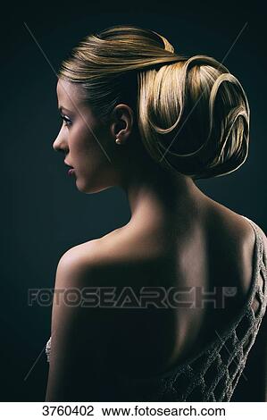 Stock Image - Portrait of a young woman wearing a bun, profile. Fotosearch