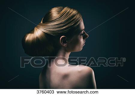 Stock Image - Portrait of a young woman wearing a bun, profile. Fotosearch