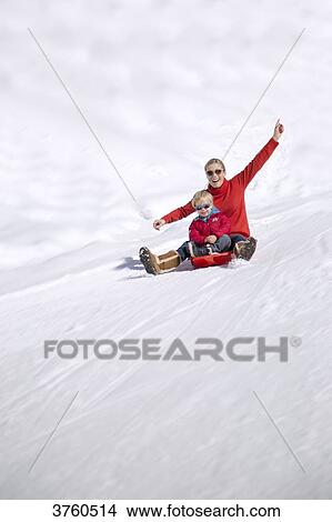Portrait of smiling woman sitting with her childs on sled in snow, Crans-Montana, Swiss Alps, Switzerland View Large Photo Image Picture - Portrait of smiling woman sitting with her childs on sled in snow, Crans-Montana, Swiss Alps, Switzerland. Fotosearch