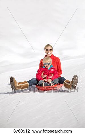 Portrait of smiling woman sitting with her childs on sled in snow, Crans-Montana, Swiss Alps, Switzerland. View Large Photo Image Stock Image - Portrait of smiling woman sitting with her childs on sled in snow, Crans-Montana, Swiss Alps, Switzerland.. Fotosearch
