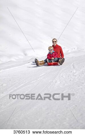 Portrait of smiling woman sitting with her childs on sled in snow, Crans-Montana, Swiss Alps, Switzerland. View Large Photo Image Stock Image - Portrait of smiling woman sitting with her childs on sled in snow, Crans-Montana, Swiss Alps, Switzerland.. Fotosearch