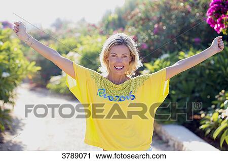 Stock Image - Portrait of young smiling woman with yellow shirt Rio 2016. Fotosearch