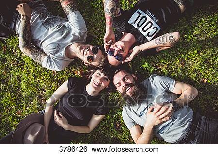 Stock Photograph - Portraits of a group of young Hipster lying in the grass. Fotosearch