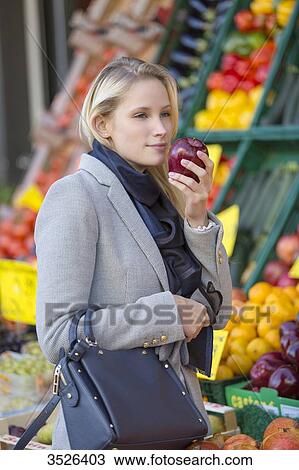 Pretty blonde woman buying healthy food on the market, smelling apple View Large Photo Image Stock Image - Pretty blonde woman buying healthy food on the market, smelling apple. Fotosearch