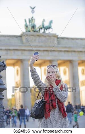 Pretty blonde woman doing a selfie and sending a kiss in front of the Brandenburg Gate in Berlin, Germany View Large Photo Image Stock Photograph - Pretty blonde woman doing a selfie and sending a kiss in front of the Brandenburg Gate in Berlin, Germany. Fotosearch
