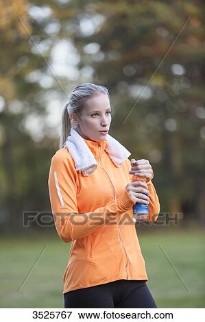 Pretty blonde woman drinking water in park after doing sport View Large Photo Image Stock Photo - Pretty blonde woman drinking water in park after doing sport. Fotosearch