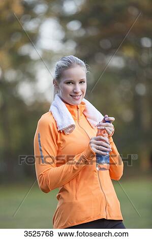 Pretty blonde woman drinking water in park after doing sport and smiling at camera View Large Photo Image Stock Photo - Pretty blonde woman drinking water in park after doing sport and smiling at camera. Fotosearch