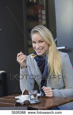 Pretty blonde woman enjoying a cake and coffee in city center smiling at camera View Large Photo Image Stock Photo - Pretty blonde woman enjoying a cake and coffee in city center smiling at camera. Fotosearch