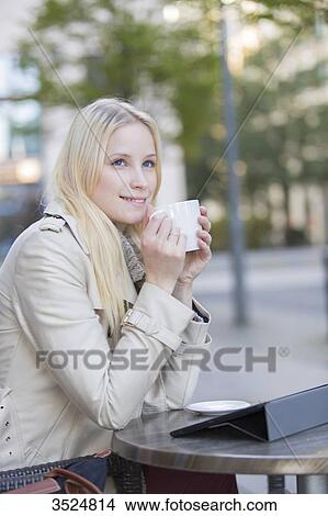 Pretty blonde woman enjoying a cup of coffee in downtow View Large Photo Image Picture - Pretty blonde woman enjoying a cup of coffee in downtow. Fotosearch