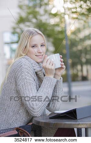 Pretty blonde woman enjoying a cup of coffee in downtown smiling at camera View Large Photo Image Stock Photo - Pretty blonde woman enjoying a cup of coffee in downtown smiling at camera. Fotosearch