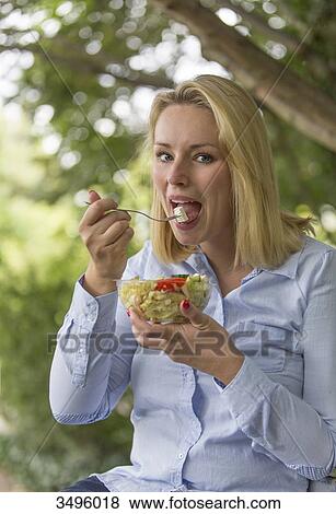 Pretty blonde woman enjoying a salad in the park View Large Photo Image Stock Photo - Pretty blonde woman enjoying a salad in the park. Fotosearch