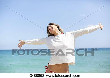 Pretty blonde woman enjoying at the beach with arms opened View Large Photo Image Stock Photo - Pretty blonde woman enjoying at the beach with arms opened. Fotosearch