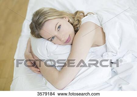 Pretty blonde woman in bed looking at camera View Large Photo Image Picture - Pretty blonde woman in bed looking at camera. Fotosearch