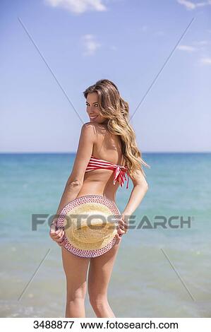Pretty blonde woman in bikini hiding her bottom at the beach smiling at camera View Large Photo Image Stock Photo - Pretty blonde woman in bikini hiding her bottom at the beach smiling at camera. Fotosearch