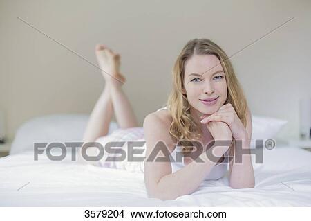 Pretty blonde woman lying in bed smiling at camera View Large Photo Image Picture - Pretty blonde woman lying in bed smiling at camera. Fotosearch