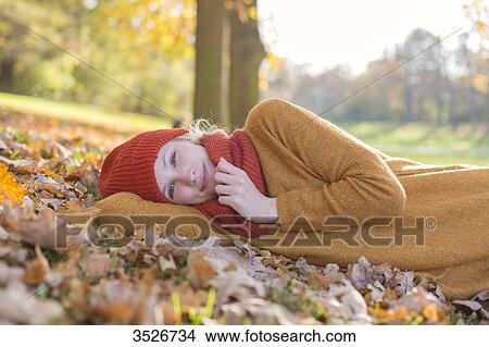 Pretty blonde woman lying in park in autumn smiling at camera View Large Photo Image Picture - Pretty blonde woman lying in park in autumn smiling at camera. Fotosearch