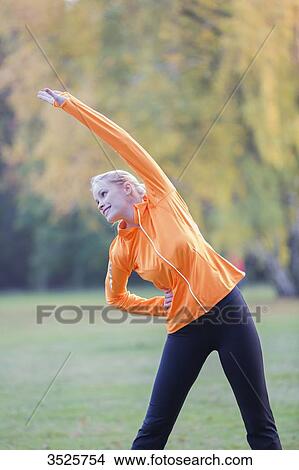 Pretty blonde woman stretching in park View Large Photo Image Picture - Pretty blonde woman stretching in park. Fotosearch